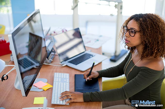 Artist websites: a woman working on her drawing on a tablet and computer. Artist websites: a woman working on her drawing on a tablet and computer.